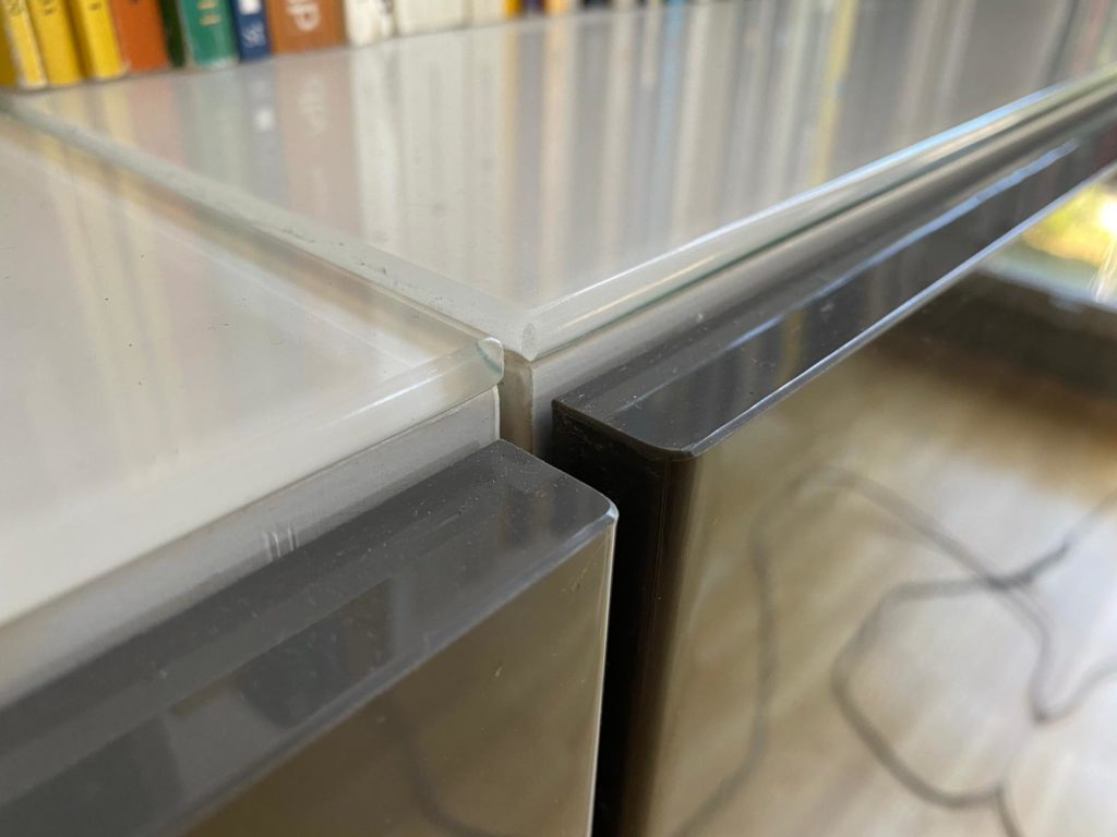 zu sehen: zweitüriges, niedriges Regal mit Lackfläche und Glasplatte, insgesamt 6 Fächer