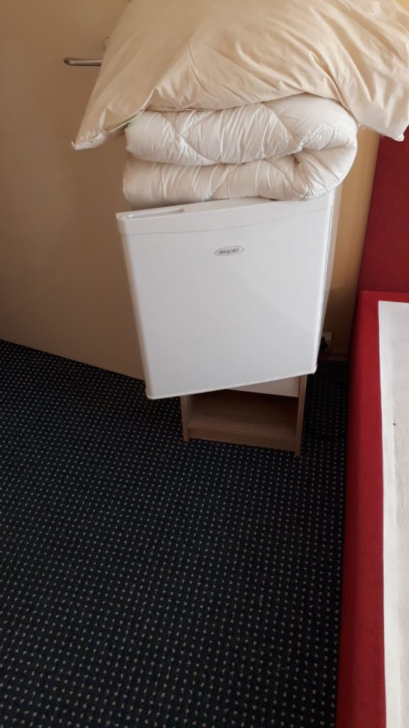 man sieht: einen kleinen Kühlschrank in einem Zimmer einer Pension ( oder Hotel )