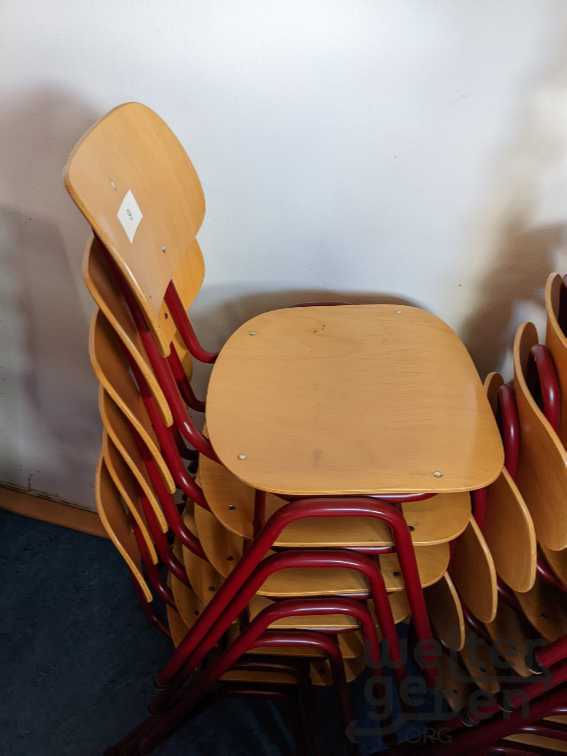 gestapelte Stühle mit Metallgestell. Lehne und Sitz aus Holz